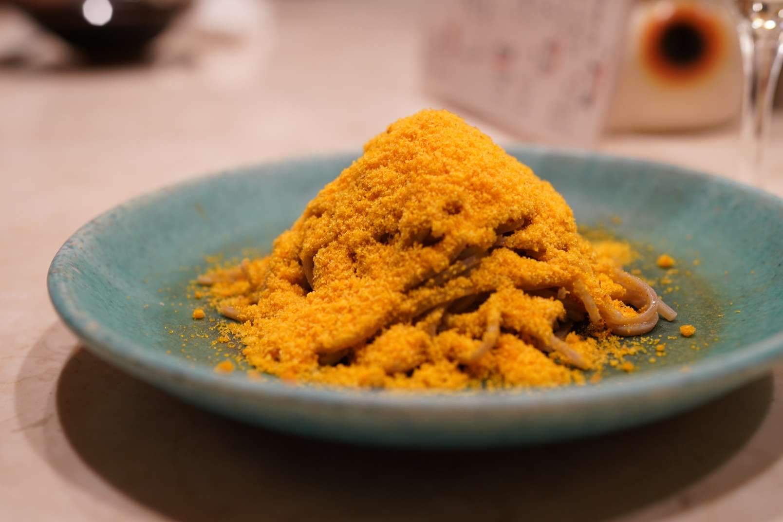 Plate of dark soba noodles with orange powder on top (Bottarga)